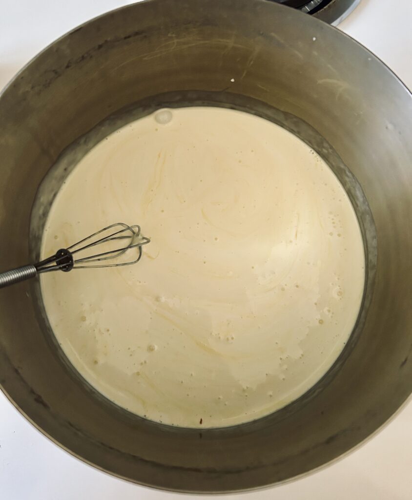 Heavy Cream heating in sauce pan with whisk