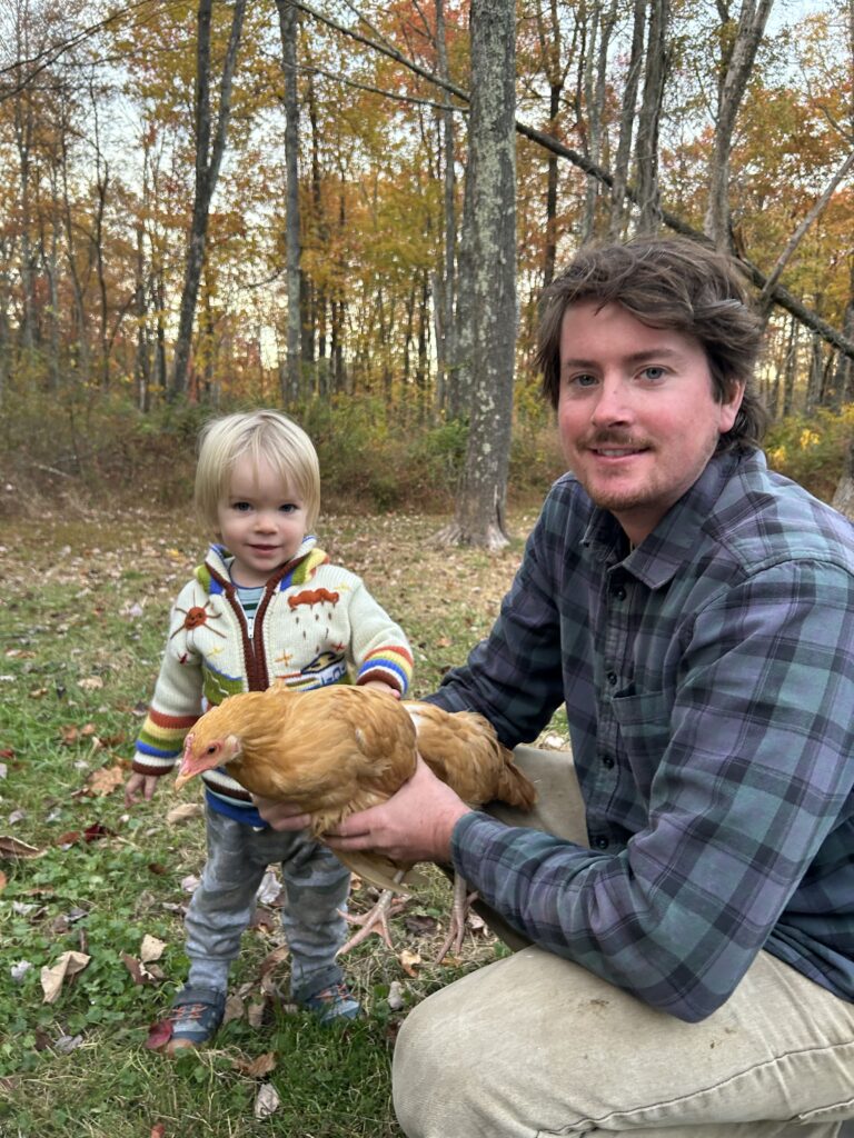 Man holding a chicken with a child on grass