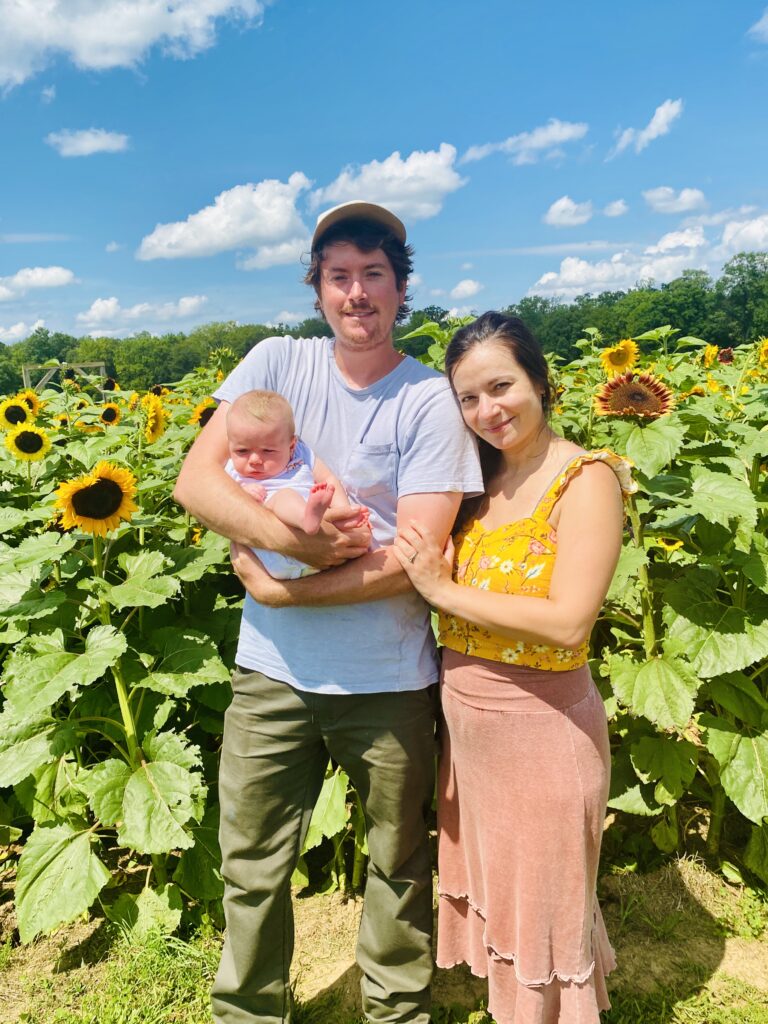 Mom and dad with baby in sunflower field