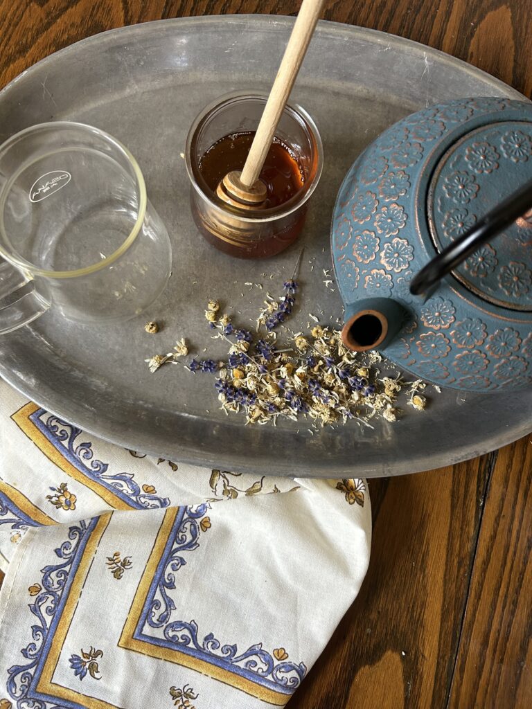 overhead shot of cast iron pot, honey, and empty tea cup. Loose herbal tea on a silver platter