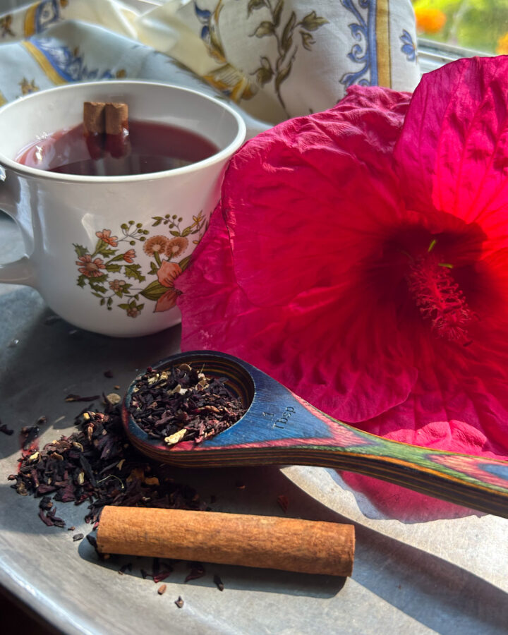 hibiscus flower, tea, wooden spoon, and loose herbal tea on a silver platter
